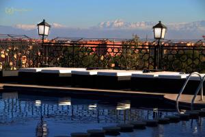 a swimming pool with lounge chairs and a view of the mountains at Hotel Imperial Plaza & Spa in Marrakesh