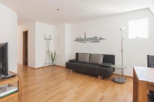 uma sala de estar com um sofá preto e uma televisão em Altstadtsuite City Center em Friburgo em Brisgóvia