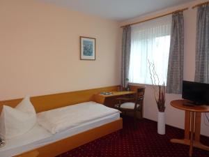 a hotel room with a bed and a desk and a window at Hotel & Gasthof Zum Löwen in Eisenach