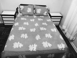een bed met een grijze deken met bladeren erop bij Apartamento Canto do Forte 200m da Praia in Praia Grande