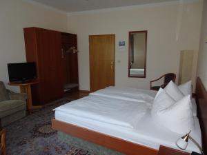 a bedroom with a large white bed and a television at Hotel & Gasthof Zum Löwen in Eisenach