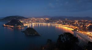 an island in the water with a city at night at Apartamento Kasa Tomas Gros in San Sebastián