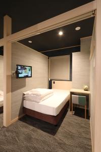 a bedroom with a bed and a flat screen tv at Cabin & Capsule Hotel J-SHIP Osaka Namba in Osaka