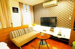uma sala de estar com um sofá e uma televisão em Nature House Homestay em Dongshan