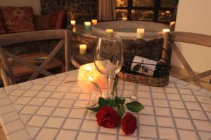 a table with a wine glass and roses on it at Volcanes in Had Nes