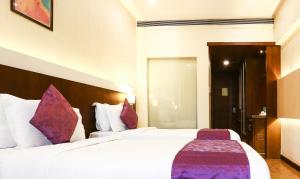 Habitación de hotel con 2 camas con almohadas moradas en Treebo Tryst Eden Residency, en Gurgaon