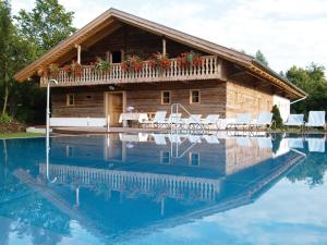a log house with a pool in front of it at Hotel Drei Quellen Therme in Bad Griesbach