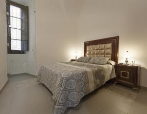 sypialnia z łóżkiem, szafką nocną i oknem w obiekcie Palacio Cáceres Deluxe w mieście Cáceres