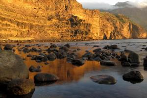 a group of rocks on a beach next to a mountain at Casa Lola in Agaete