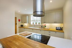 cocina con armarios blancos y mesa de madera en 1 Luzon Dove Barn en Stoke on Trent