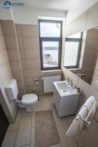 La salle de bains est pourvue de toilettes blanches et d'un lavabo. dans l'établissement Citadel Aparthotel, à Galaţi