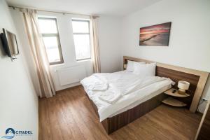 1 dormitorio con 1 cama grande con sábanas blancas en Citadel Aparthotel, en Galaţi