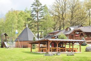 a large wooden house with a playground in the yard at Resort Hulín in Sedlčany