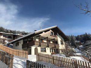 une maison avec une clôture en bois dans la neige dans l'établissement Haus Peskoller, à Perca