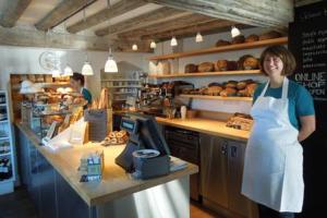 a woman is standing in a bakery kitchen at Crown Cottage - Prime Orford Location in Orford