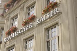 a sign on the side of a building with flowers at Hotel Römischer Kaiser in Trier