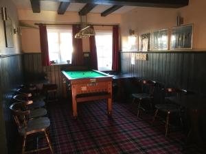 a room with a pool table and some chairs at The White Hart pub and rooms in Cranleigh