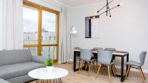 a living room with a couch and a table and chairs at Glow Apartments, Apartament Mila Baltica in Gdańsk