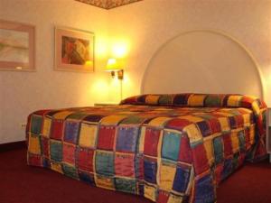 a bedroom with a bed with a colorful blanket at O'Hare Inn & Suites in Schiller Park