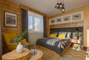 een slaapkamer met een bed en een gele stoel bij Dom Gościnny Bachledova in Zakopane