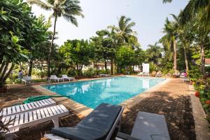 a swimming pool with lounge chairs and palm trees at Tobias Villas in Cavelossim