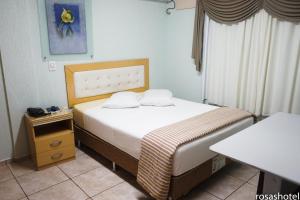 ein kleines Schlafzimmer mit einem Bett und einem Tisch in der Unterkunft Rosa's Hotel in Toledo
