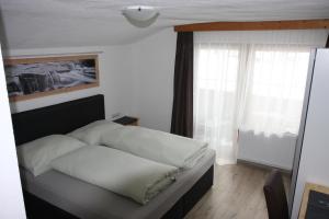 a bedroom with a bed with white sheets and a window at Haus Eckhart in Kaunertal