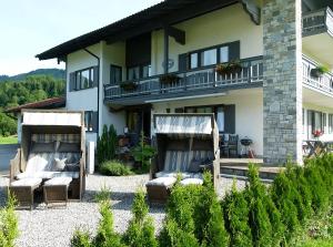 a house with chairs and a patio in front of it at Gästehaus Pointner in Ruhpolding