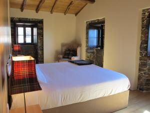 ein Schlafzimmer mit einem großen weißen Bett in einem Zimmer in der Unterkunft Casa do Talasnal in Lousã