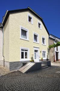 un edificio giallo con finestre bianche su una strada di mattoni di Gaestehaus Gaes a Trittenheim