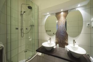 a bathroom with two sinks and a shower and mirrors at Hotel am Berg in Frankfurt/Main