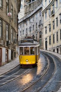 a yellow and black train traveling down tracks at Vincci Baixa in Lisbon