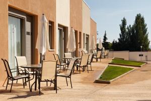 RuralSuite Hotel Apartamentos في Cascante: صف من الطاولات والكراسي مع مظلات بيضاء