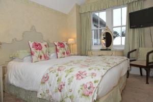 una camera da letto con un grande letto con fiori rosa di The Inglenook Hotel a Bognor Regis