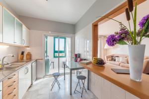 フンシャルにあるFalesia Apartment by LovelyStayのキッチン(紫の花のテーブル付)