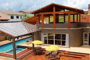 马沙蒂纽Hotel Villa das Termas Machadinho的一座带游泳池和黄伞甲板的房子