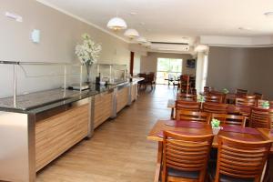 马沙蒂纽Hotel Villa das Termas Machadinho的餐厅设有木桌、椅子和柜台