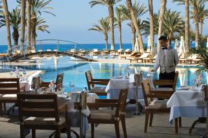a dining room table with chairs and umbrellas at Constantinou Bros Asimina Suites Hotel in Paphos City