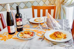 a table with two plates of pasta and a bottle of wine at Hotel Dolcevita in Cesenatico