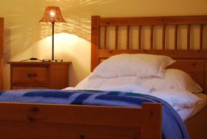 - une chambre avec un lit doté d'une couverture bleue et d'une lampe dans l'établissement Jackfall Apartman és Fogadó, à Kisjakabfalva