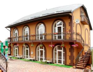 - un grand bâtiment orange avec un balcon et des escaliers dans l'établissement Sadyba Smotrytska Perlyna, à Kamianets-Podilsky