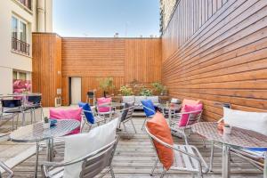 d'une terrasse avec des tables et des chaises et un mur en bois. dans l'établissement Mercure Paris Bastille Marais, à Paris