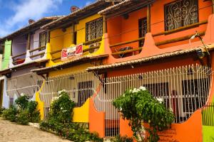 an orange and yellow building with windows and plants at Apartamentos Pipa Centro in Pipa