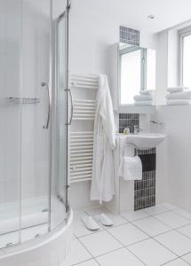 a white bathroom with a shower and a sink at SACO Holborn – Lamb’s Conduit St in London