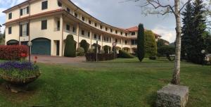 un grande edificio bianco con un cortile fiorito di Centro di Spiritualità Maria Candida ad Armeno