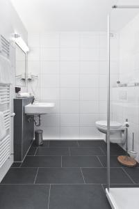 a white bathroom with a sink and a toilet at Hotel Klinkner in Emmelshausen