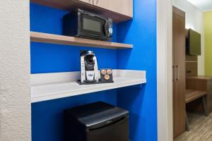 a room with a blue wall and a tv on a shelf at Holiday Inn Express & Suites - Columbus Airport East by IHG in Columbus