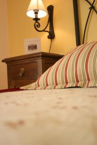 Una cama con lámpara y una almohada. en Mesón de la Molinera, en Arcos de la Frontera