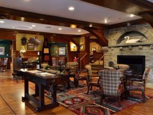 a living room with a stone fireplace and a table and chairs at Bob Timberlake Inn at Chetola Resort in Blowing Rock