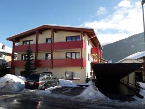 een auto geparkeerd voor een gebouw in de sneeuw bij Family-Appartements in Innsbruck